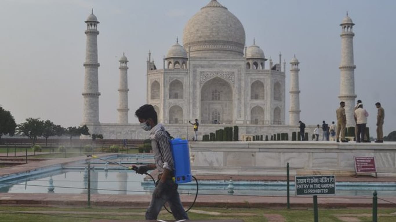 Ein Mann sprüht Desinfektionsmittel in einem Bereich vor dem Taj Mahal im nordindischen Agra.