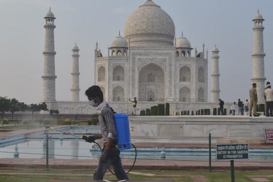 Ein Mann sprüht Desinfektionsmittel in einem Bereich vor dem Taj Mahal im nordindischen Agra.