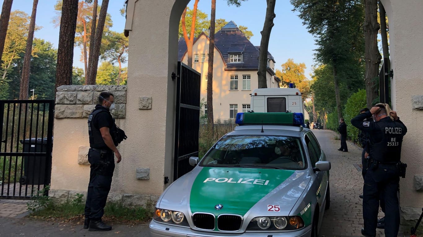 Ein Polizeiauto steht in einem Torbogen: Auch die Villa des Clanchefs in Kleinmachnow ist durchsucht worden.