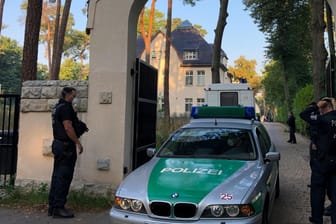 Ein Polizeiauto steht in einem Torbogen: Auch die Villa des Clanchefs in Kleinmachnow ist durchsucht worden.