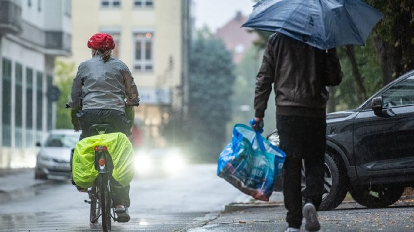Ein Radfahrer und ein Mann mit Regenschirm