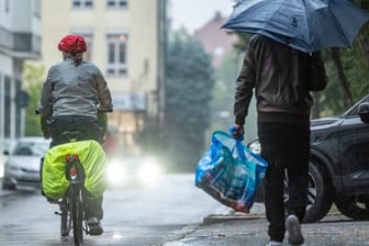 Ein Radfahrer und ein Mann mit Regenschirm