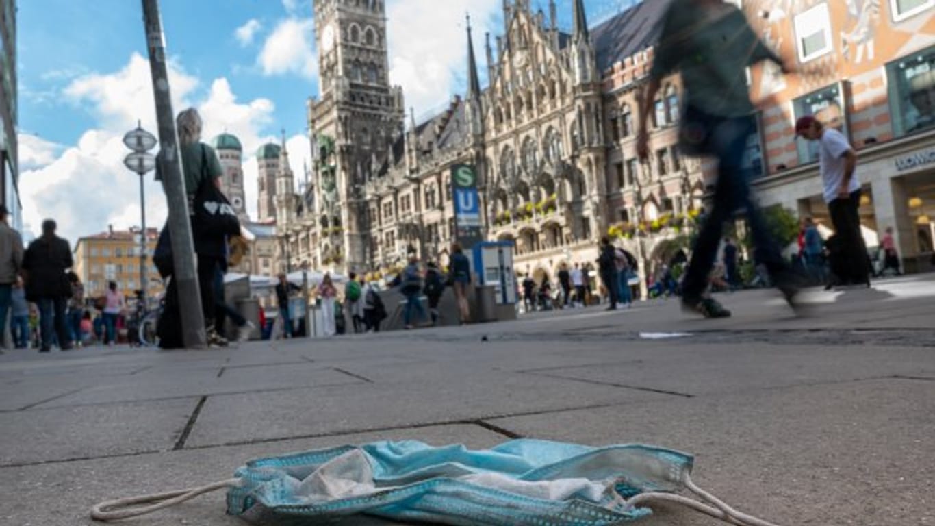 Eine getragene Mundschutzmaske liegt in der Fußgängerzone: In München gelten seit Donnerstag verschärfte Corona-Regeln.