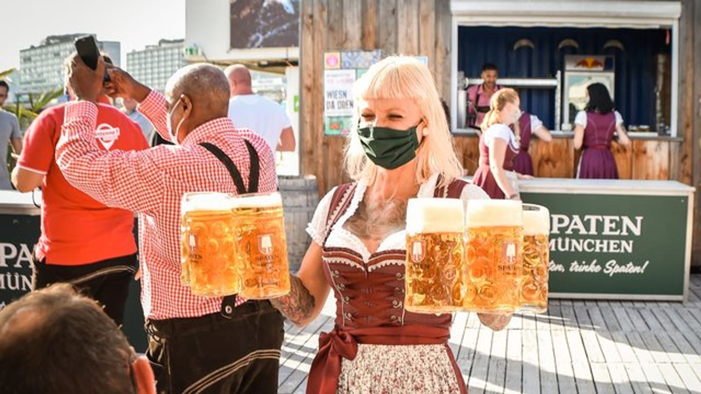 Eine Bedienung trägt Biergläser (Archivbild): In Stuttgart wird in vielen Lokalen ein Ersatz-Wasen gefeiert.