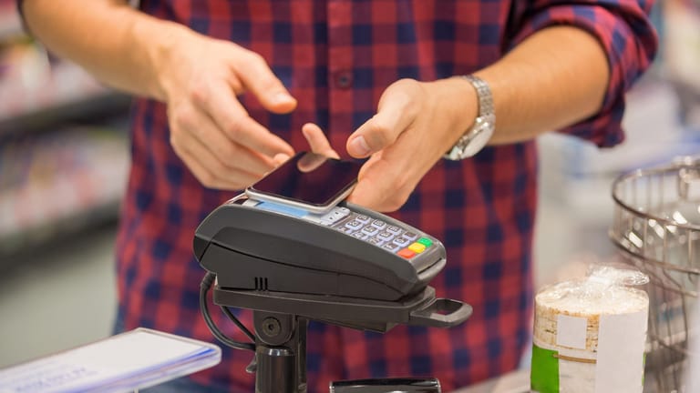 Ein Mann bezahlt mit dem Smartphone (Symbolbild): Samsung tritt mit einer eigenen Pay-App gegen Google und Apple an.