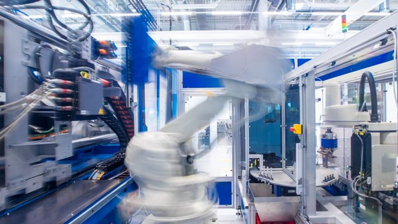 Ein Industrieroboter nimmt unter Reinraumbedingungen einen Halter für Insulinspritzen in einer Produktionshalle eines neu errichteteten Werks des Schweizer Medizintechnikunternehmens Ypsomed aus einer Maschine.