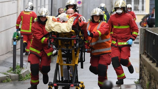 Einsatzkräfte der Feuerwehr schieben eine Trage mit einem Verletzten.