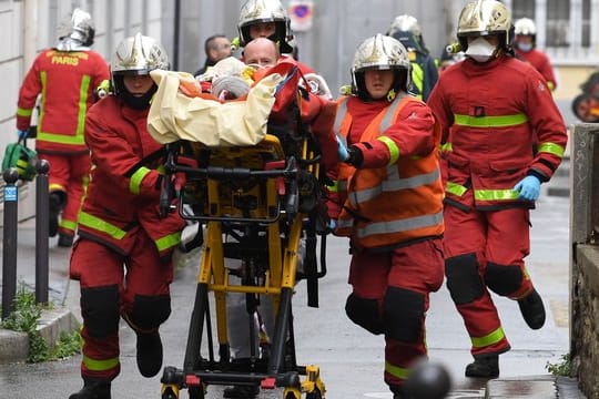 Einsatzkräfte der Feuerwehr schieben eine Trage mit einem Verletzten.