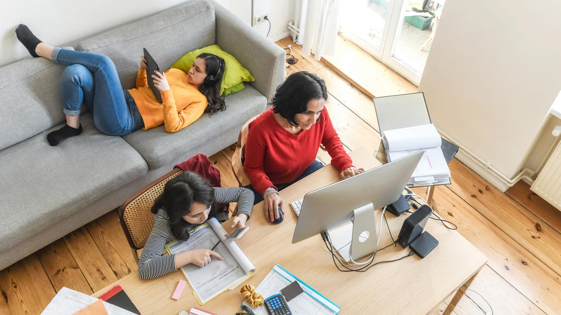 Eine Mutter mit zwei Töchtern im Homeoffice (Symbolbild): Wer zu Hause arbeitet, zahlt mehr für Strom.