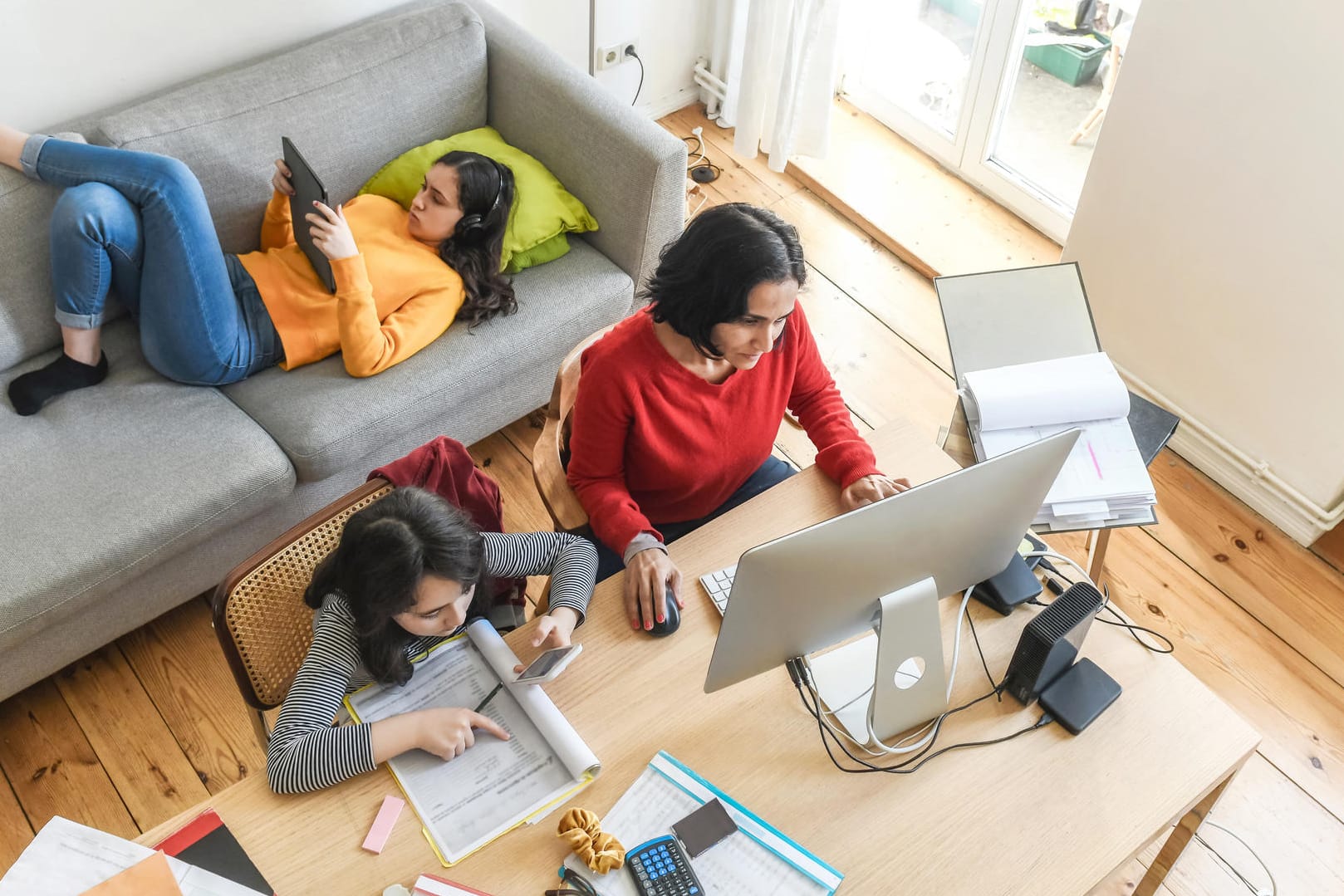 Eine Mutter mit zwei Töchtern im Homeoffice (Symbolbild): Wer zu Hause arbeitet, zahlt mehr für Strom.