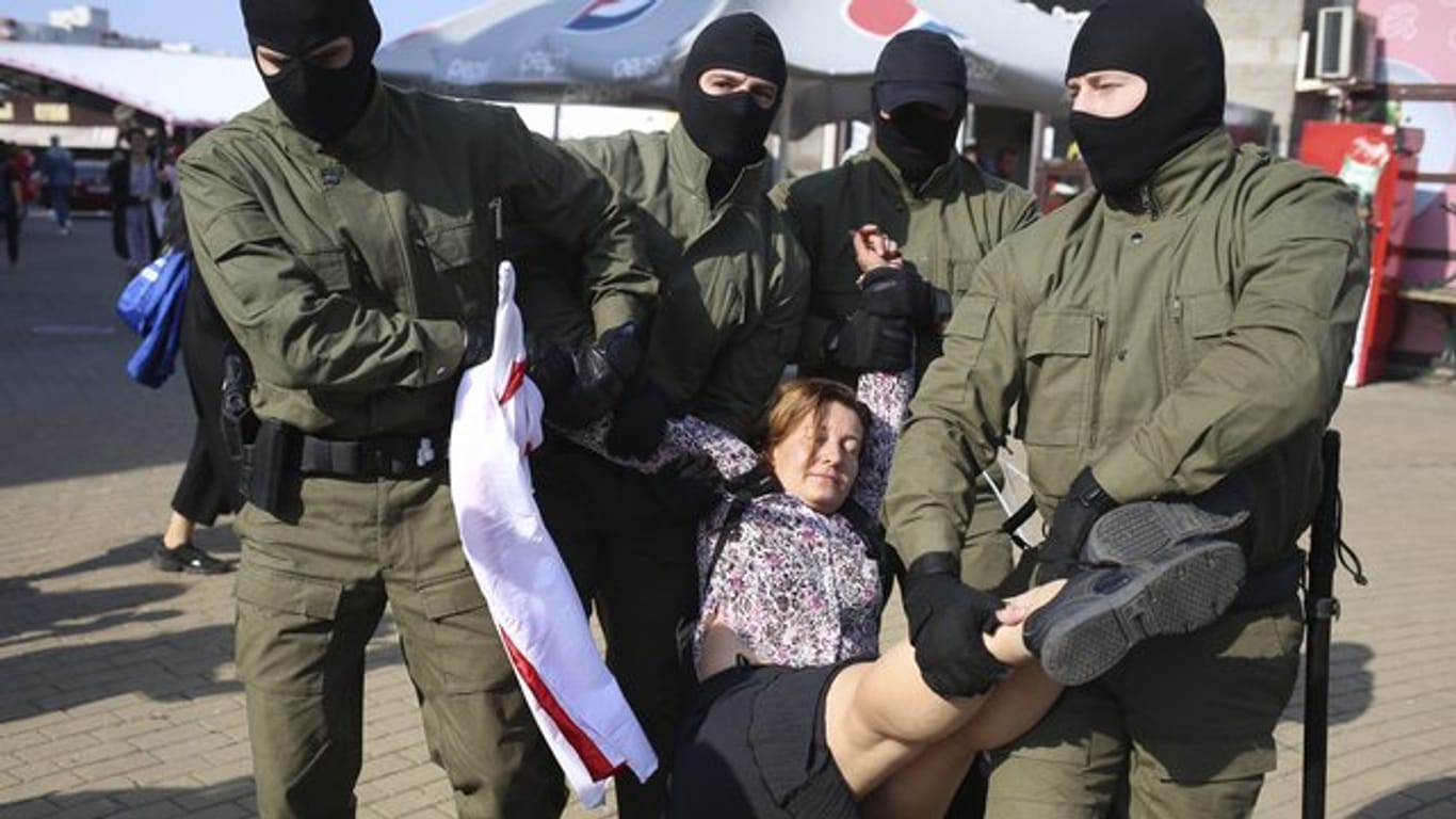 Polizisten tragen am Rande einer Demonstration in Minsk eine Frau weg.