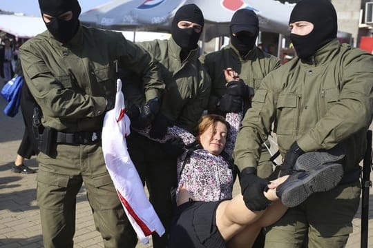 Polizisten tragen am Rande einer Demonstration in Minsk eine Frau weg.