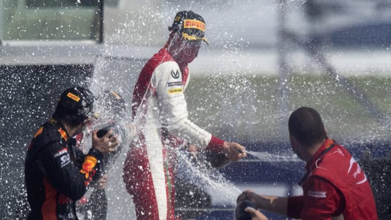 Formel-2-Pilot Mick Schumacher (M) feiert seinen Sieg in Sotschi mit Champagner.
