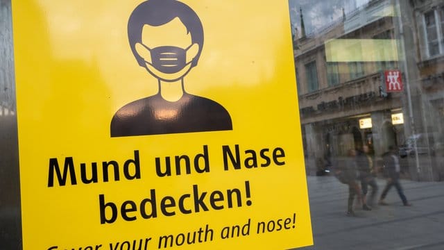 Auf dem Münchener Marienplatz fordert ein Schild zum Tragen eine Mund-Nasen-Bedeckung auf. Auf dem Münchener Marienplatz fordert ein Schild zum Tragen eine Mund-Nasen-Bedeckung auf.