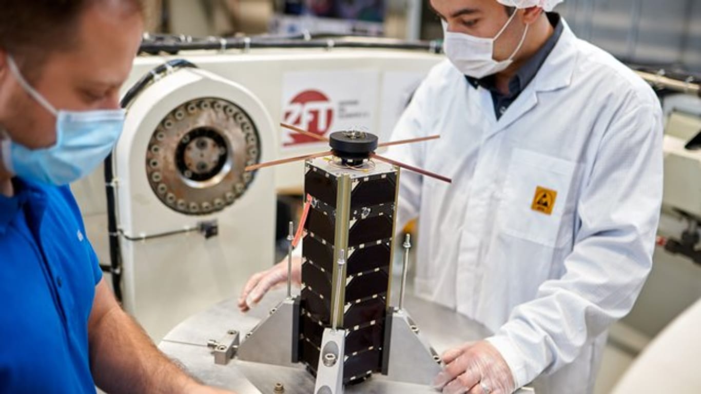 Zwei Mitarbeiter bereiten einen NetSat-Satelliten zum Test auf dem hochdynamischen Drehtisch vor.