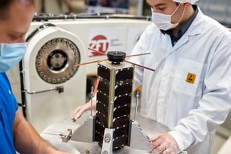 Zwei Mitarbeiter bereiten einen NetSat-Satelliten zum Test auf dem hochdynamischen Drehtisch vor.