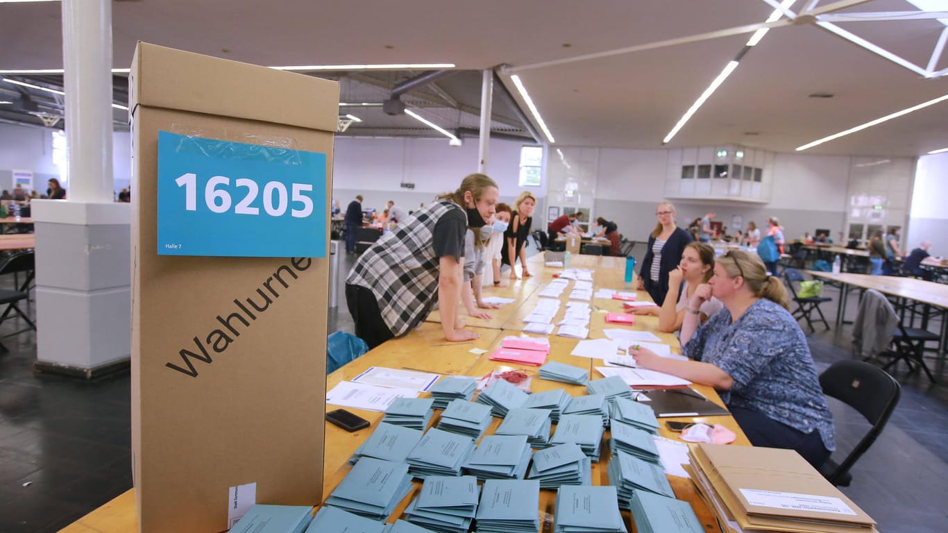 Wahlhelfer sitzen an einem Tisch mit Wahlunterlagen (Symbolbild): Stadt Dortmund zieht positive Bilanz nach Stichwahl.