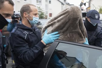 Beamte des Zoll führen den in Frankfurt festgenommenen Hauptbeschuldigten mit einer Decke über dem Kopf ab.