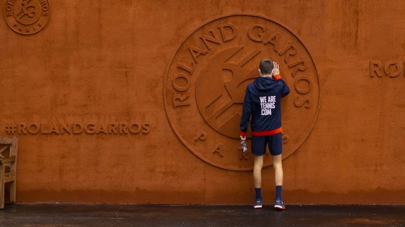 Ein Balljunge berührt das Logo vom Stade Roland Garros.