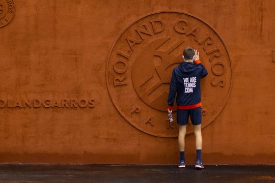 Ein Balljunge berührt das Logo vom Stade Roland Garros.