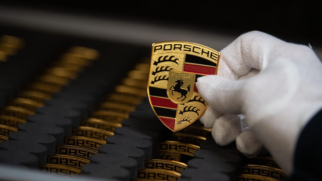 Ein Porsche-Mitarbeiter hält das Wappen das Sportwagenherstellers (Symbolbild): Porsche wird verdächtigt, auch beim Abgas-Verbrauch von Benzinern manipuliert zu haben.