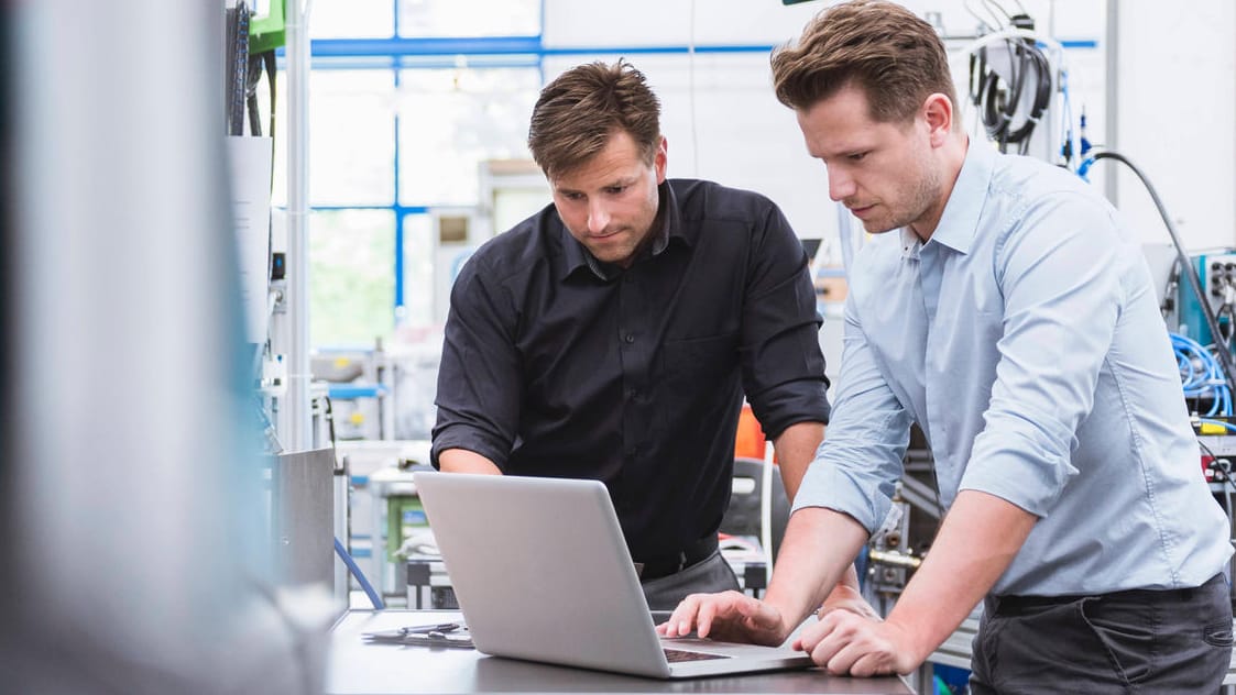 Zwei Männer an einem Computer in einem Unternehmen: Rund die Hälfte der deutschen Unternehmen hat Cyber-Angriffe erlitten