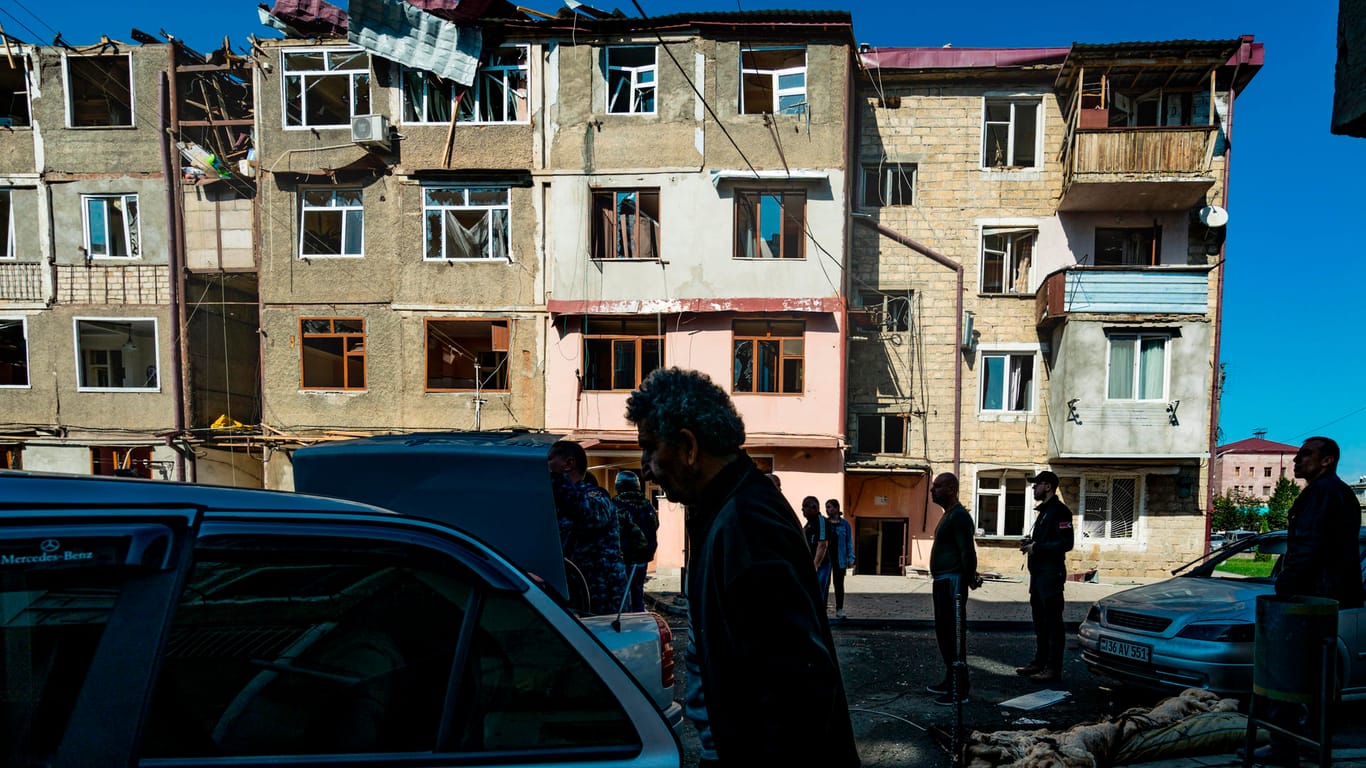 Aserbaidschan, Stepanakert: Anwohner stehen vor einem von Beschuss beschädigten Haus.