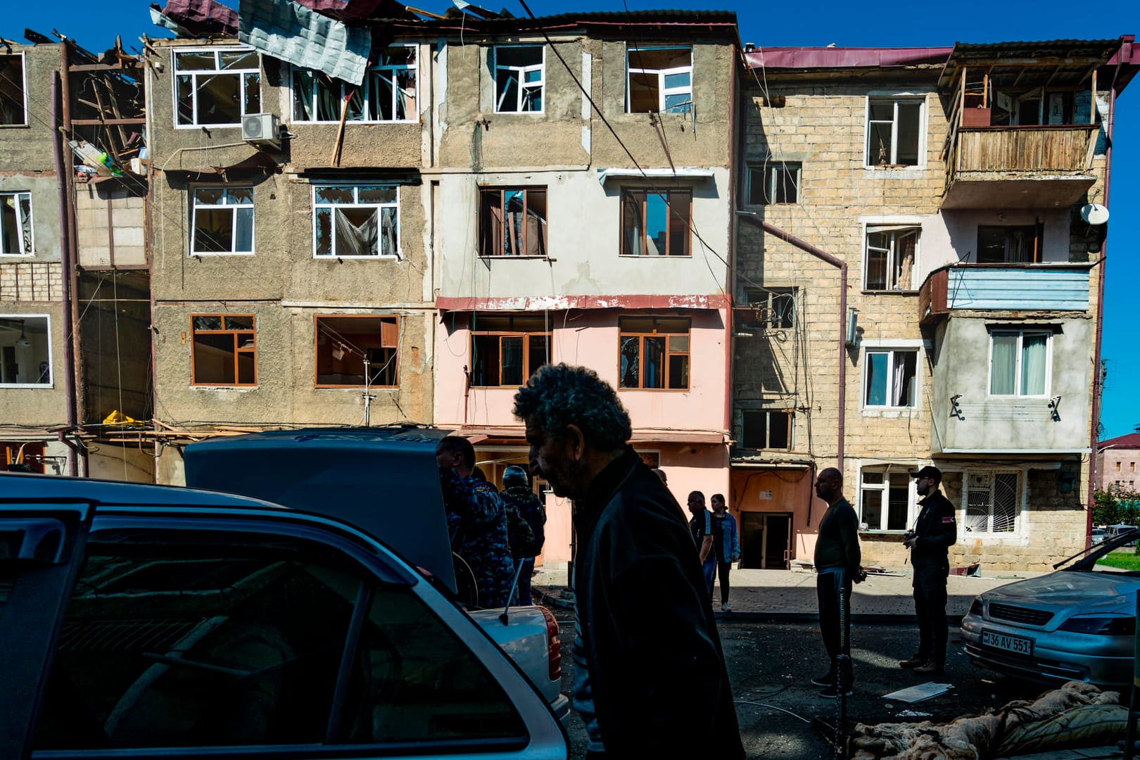 Aserbaidschan, Stepanakert: Anwohner stehen vor einem von Beschuss beschädigten Haus.