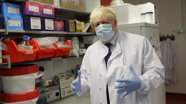 Boris Johnson, Premierminister von Großbritannien, gestikuliert mit seinen Händen und trägt Schutzkleidung und Maske.