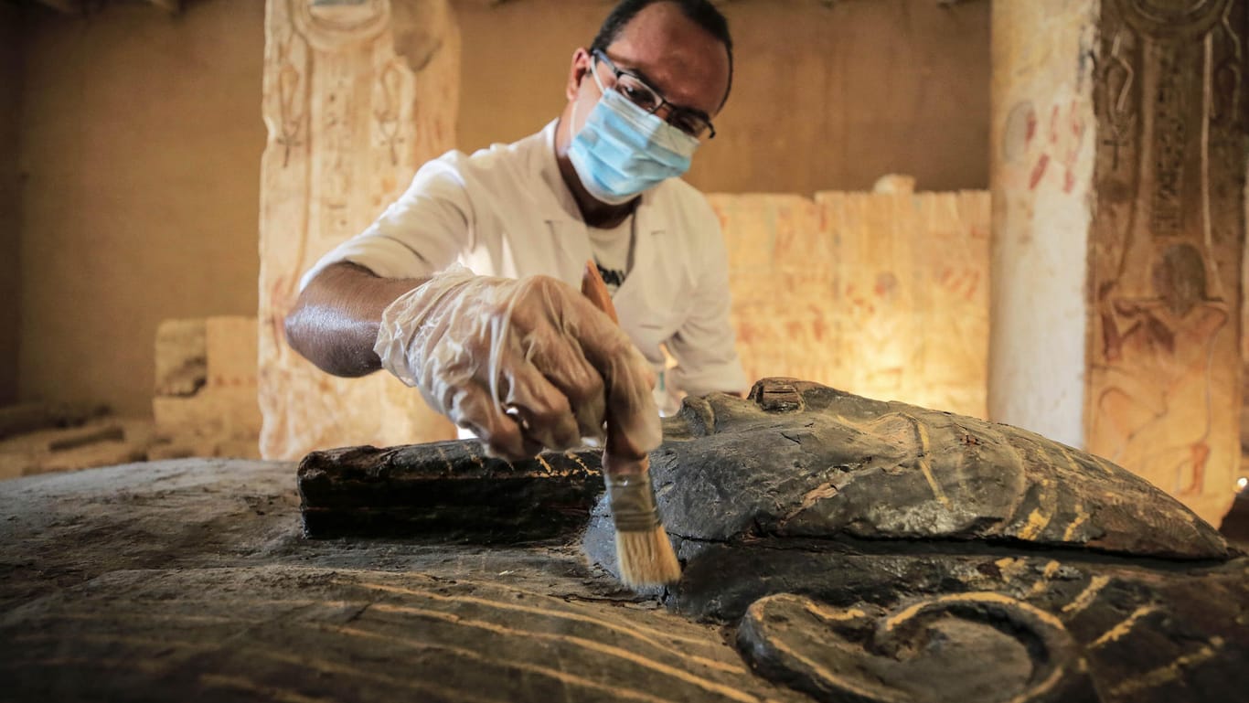 Ägypten, Gizeh: Ein ägyptischer Archäologe entfernt Staub aus einem der neu entdeckten Särge.