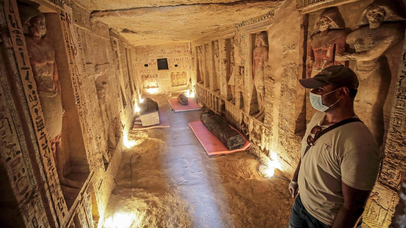 Ägypten, Gizeh: Ein Mann steht in einem neu entdeckten Schacht, während einige der neu entdeckten Särge auf den Boden gelegt werden.