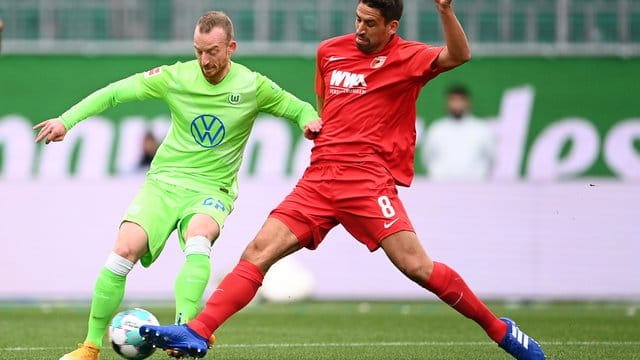 Wolfsburgs Maximilian Arnold (l) kämpft mit Augsburgs Rani Khedira um den Ball. Wolfsburgs Maximilian Arnold (l) kämpft mit Augsburgs Rani Khedira um den Ball.