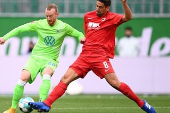Wolfsburgs Maximilian Arnold (l) kämpft mit Augsburgs Rani Khedira um den Ball.