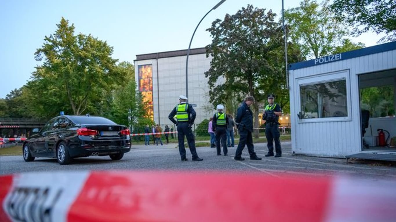 Polizeibeamte und Zivilisten stehen im abgesperrten Bereich vor der Synagoge in Hamburg-Harvestehude.
