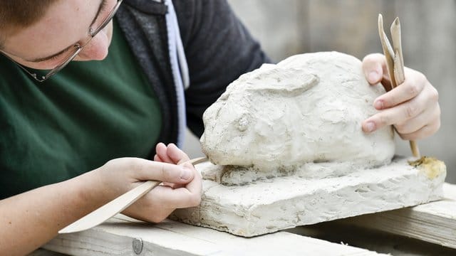 Die Auszubildende Steinbildhauerin Lena Tilsner modelliert in der Steinbildhauerwerkstatt von Rainer Kühn an einer Hasenfigur.