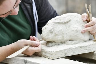 Die Auszubildende Steinbildhauerin Lena Tilsner modelliert in der Steinbildhauerwerkstatt von Rainer Kühn an einer Hasenfigur.