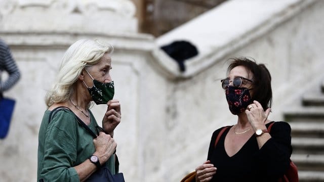 Zwei Frauen mit Masken stehen vor einer Treppe in Rom. Zwei Frauen mit Masken stehen vor einer Treppe in Rom.