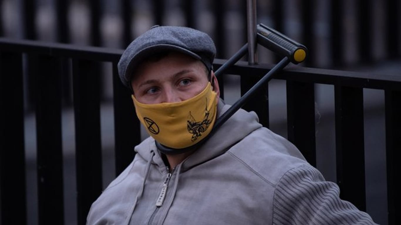 Ein Umweltaktivist von Extinction Rebellion (XR) hat sich mit einem Bügelschloss an einem Gitter am Bundesverkehrsministerium angeschlossen.