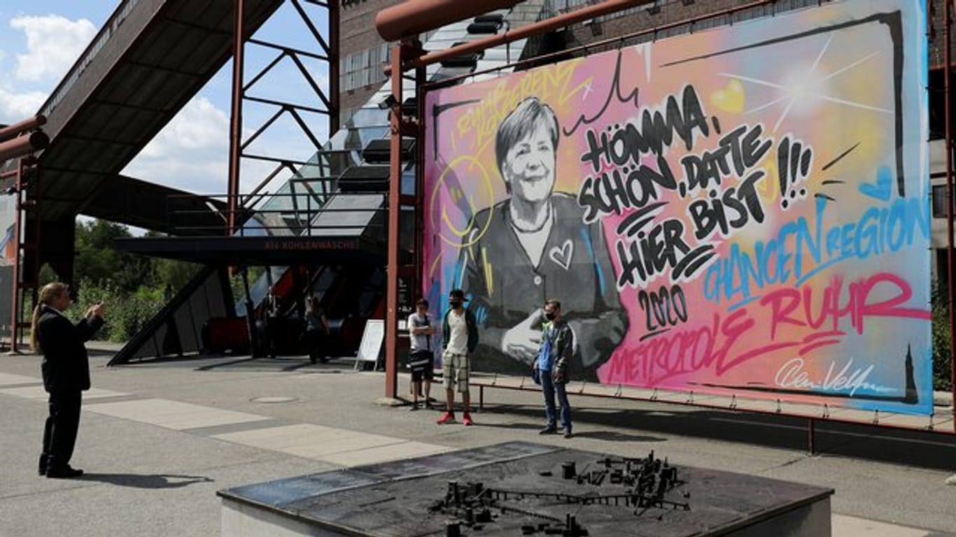 Touristen lassen sich vor dem Merkel-Graffiti in Essen ablichten