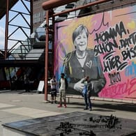 Touristen lassen sich vor dem Merkel-Graffiti in Essen ablichten