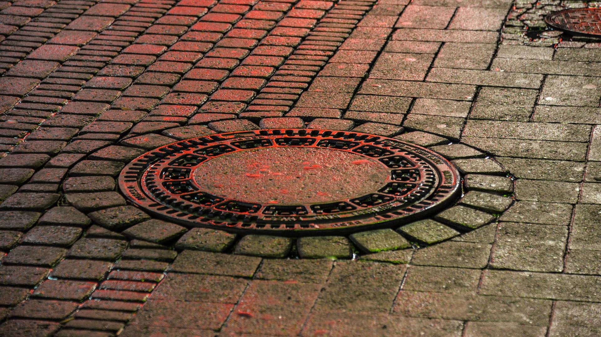 Ein Gully im Abendlicht (Symbolbild): Eine Frau hat sich ihre Hand in einem Gullydeckel eingeklemmt. Ein Gully im Abendlicht (Symbolbild): Eine Frau hat sich ihre Hand in einem Gullydeckel eingeklemmt.