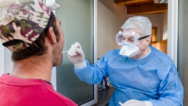 Eijn Arzt führt bei einem Mann in Wesselburen einen Corona-Test durch.