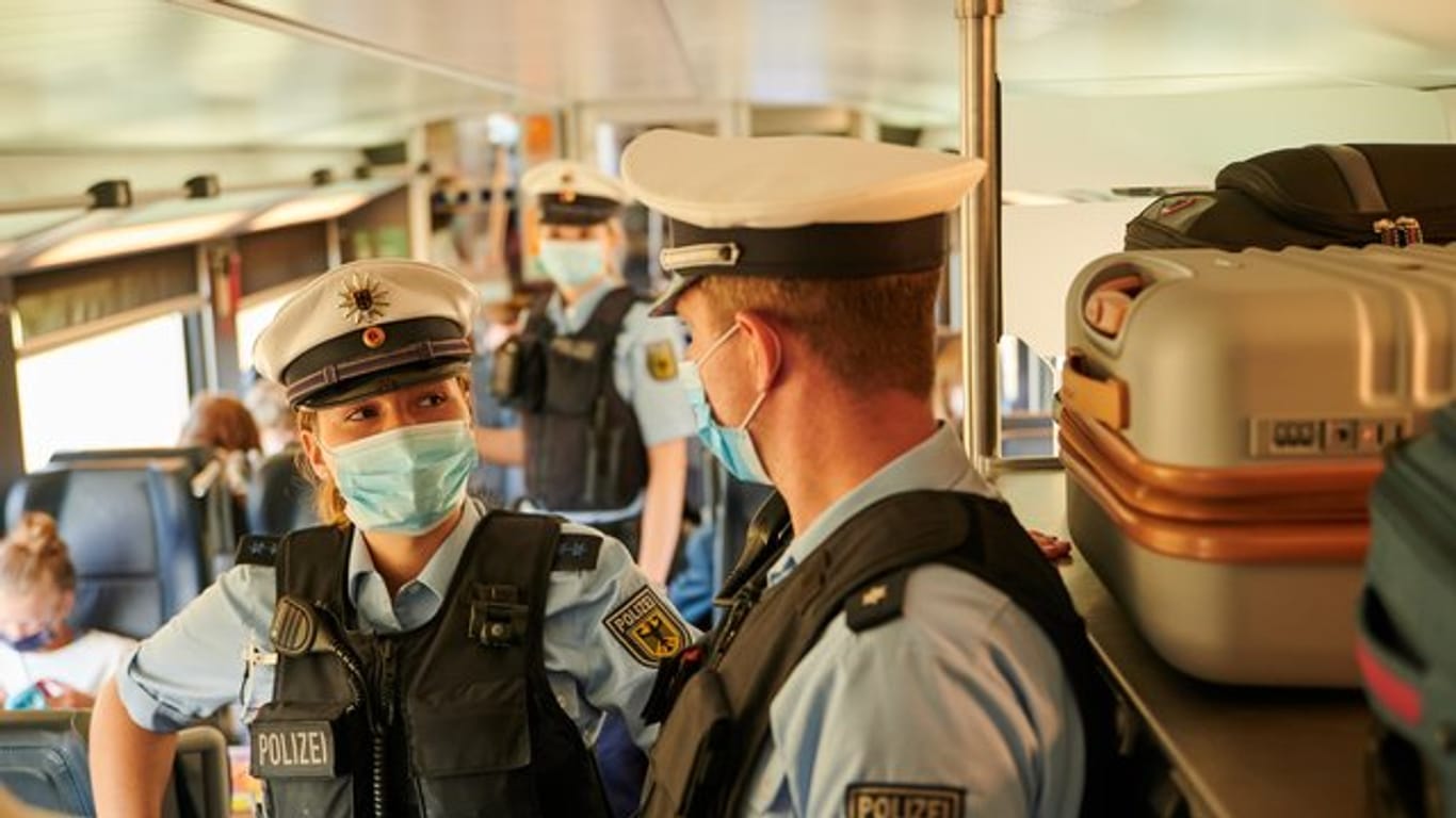 Beamte der Bundespolizei und Mitarbeiter der DB Sicherheit kontrollieren in einem ICb die coronabedingte Maskenpflicht.