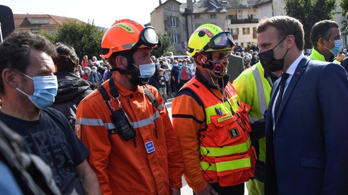 Der französische Präsident Emmanuel Macron (r) trifft Rettungskräfte während eines Besuchs in Tende im Südosten Frankreichs nach den schweren Unwettern.