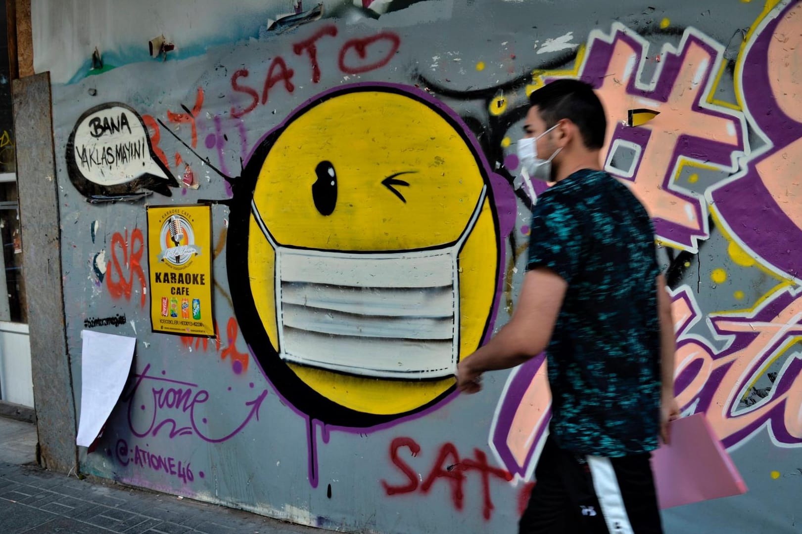 Ein Graffiti eines Emojis, das Maske trägt: Apple führt ein neues Masken-Emoji ein.