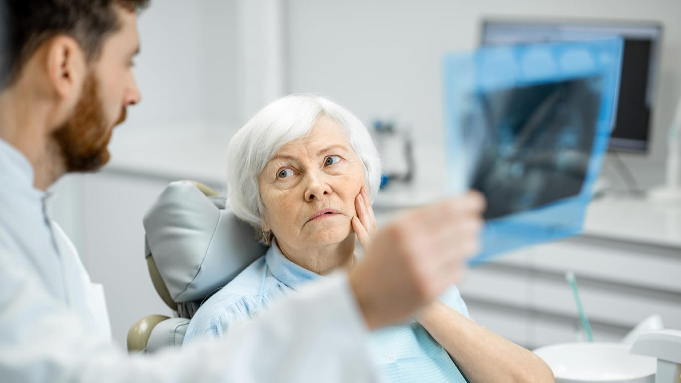 Eine ältere Frau beim Zahnarzt: Der Östrogenverlust in der Post-Menopause schwächt die Knochen. Davon betroffen ist auch der Kiefer.