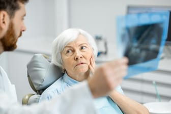 Eine ältere Frau beim Zahnarzt: Der Östrogenverlust in der Post-Menopause schwächt die Knochen. Davon betroffen ist auch der Kiefer.