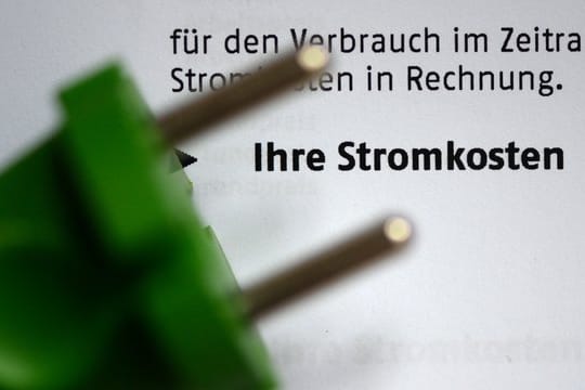 Ein grüner Stromstecker liegt auf einer Stromrechnung