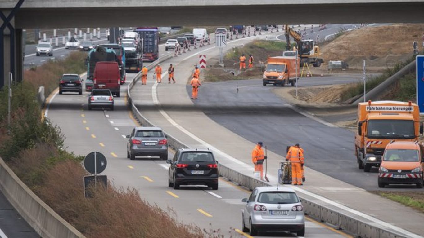 Bauarbeiter stehen in einer Baustelle auf der Autobahn A7