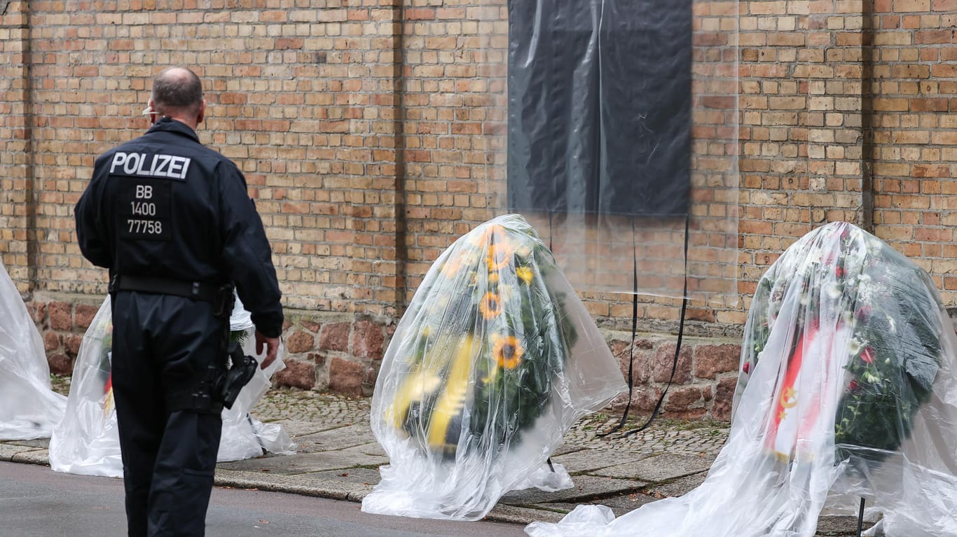Ein Polizist steht vor verpackten Kränzen für den Gedenktag an den Anschlag vor der Synagoge in Halle: Beim Gedenken in Köln soll ein Zivilbeamter durch seine Kleidung aufgefallen sein.